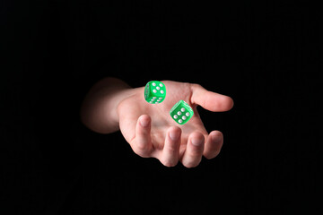 Man throwing green dice in darkness, closeup