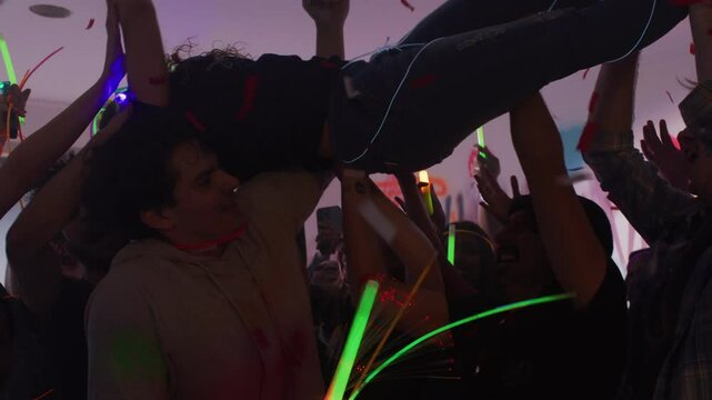 A girl crowd surfs over a crowd of people at a super fun house party.