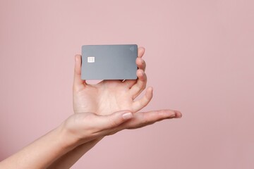 Close up elegant hand hold a blank credit card with online service for mockup isolated on pink background. Modern way of banking and buying