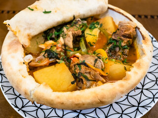 Khashlama in bowl covered with baked fllat bread