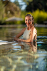  A stylish woman posing confidently in a luxurious pool, surrounded by a serene and relaxing summer atmosphere.