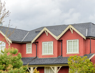 Top of grey stucco luxury house with shingle roof, red and yellow trees and nice windows in Summer in Vancouver, Canada, North America. Day time on June 2024.