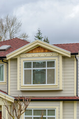 Top of grey stucco luxury house with shingle roof, red and yellow trees and nice windows in Summer in Vancouver, Canada, North America. Day time on June 2024.