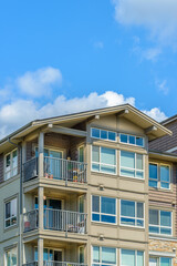 Top of grey stucco luxury house with shingle roof, red and yellow trees and nice windows in Summer in Vancouver, Canada, North America. Day time on June 2024.