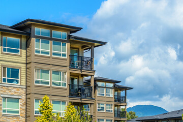Top of grey stucco luxury house with shingle roof, red and yellow trees and nice windows in Summer in Vancouver, Canada, North America. Day time on June 2024.