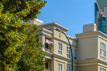 Top of grey stucco luxury house with shingle roof, red and yellow trees and nice windows in Summer in Vancouver, Canada, North America. Day time on June 2024.