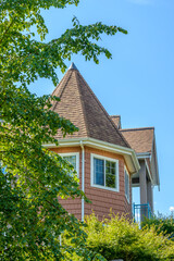 Top of grey stucco luxury house with shingle roof, red and yellow trees and nice windows in Summer in Vancouver, Canada, North America. Day time on June 2024.