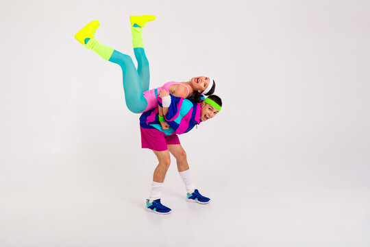 Energetic couple having fun in vibrant retro activewear on a white background, showcasing lively expressions and dynamic poses