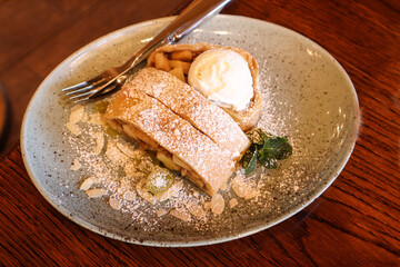 Apple strudel sprinkled with sugar on a wooden table, top view