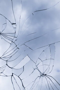 broken glass window with cracks and lines background reflecting the blue sky
