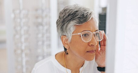 Mature woman, glasses and choice in mirror at clinic for healthy vision, wellness and optometry...