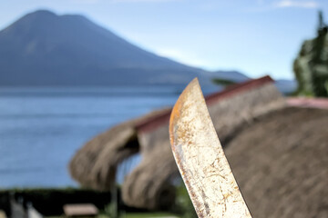 rusty machete knife with view of tropical landscape (scenic travel tourism destination lake atitlan...