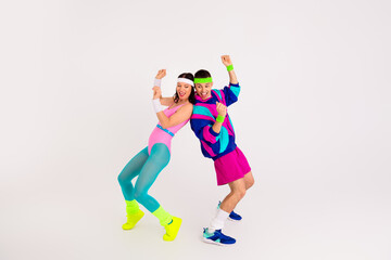 Energetic couple wearing vibrant retro fitness outfits, posing playfully against a white background.