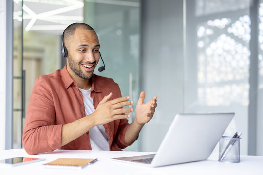 Professional man in office participates in a virtual meeting using a headset and laptop. Demonstrates concepts of technology, communication, and collaboration through online interactions in a work