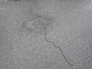 asphalt road with broken cracks after rain