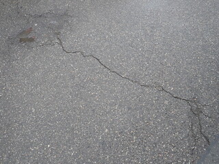 asphalt road with broken cracks after rain