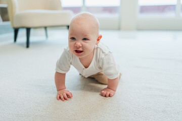Happy baby. Cute little newborn girl with smiling face crawling on floor in bedroom. Infant baby resting playing in living room indoor at home. Motherhood happy child childcare concept