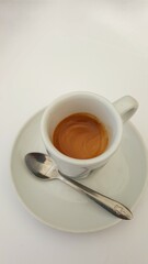 Uma xícara de café curto de portugal, no pires, e colher.