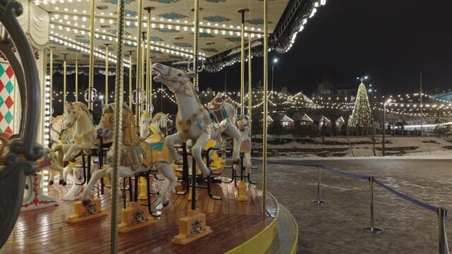 Illuminated Merry go round spinning.  Empty old fashion roundabout in park.