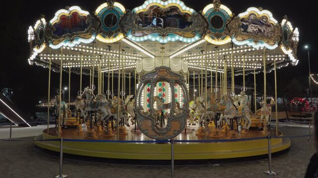 Illuminated Merry go round spinning.  Empty old fashion roundabout in park.