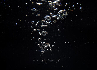 Bubbles and silver particles floating in dark water creating a mesmerizing effect