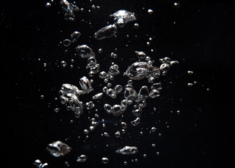 Bubbles and silver particles floating in dark water creating a mesmerizing effect