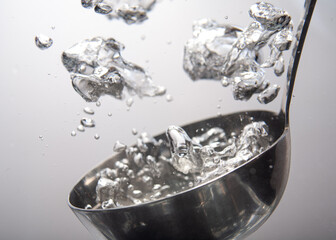Water splashes dramatically from a metallic ladle in a kitchen setting