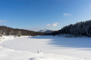 A snowy mountain lake in winter with a blue sky