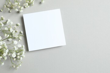 Top view photo with paper card and gypsophila flowers on gray background 