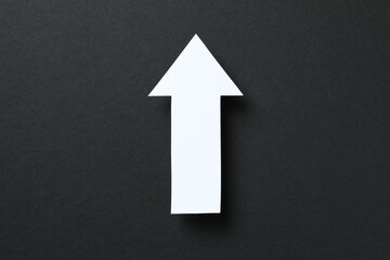 Paper arrow on black background, top view