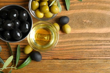 Bowl of fresh olive oil and olives with leaves on the table