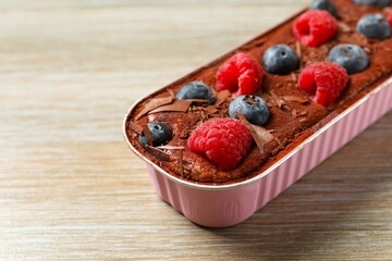 Delicious tiramisu cake with berries on table