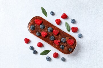 Delicious tiramisu cake with berries on table