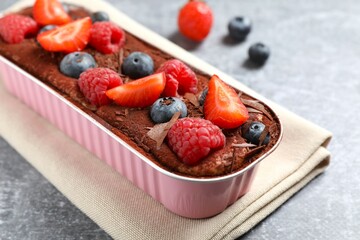 Delicious tiramisu cake with berries on table