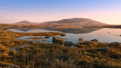 Beautiful sunrise landscape scenery of Mullaghmore mountain reflected in Lake at Burren National...