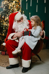 Little girl receiving a gift from Santa Claus during a joyful holiday celebration