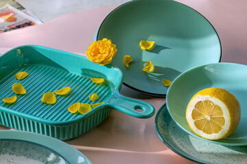 Trendy turquoise tableware. On pink background. Serving utensils in fashionable turquoise color. Ceramics, porcelain.