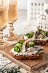 Little sandwiches bruschettas with pieces of salted herring cream cheese and cucumber. Traditional new year appetizer. Festive table