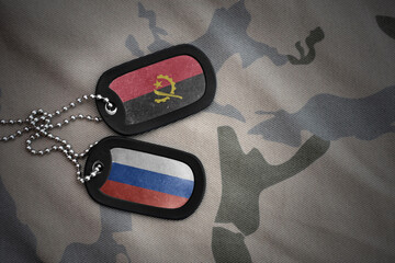 vintage army blank, dog tag with flag of angola and russia on the khaki texture background....