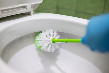 Cleaning lavatory pan with brush. Toilet hygiene at home, cleaning lavatory pan under the rim where...