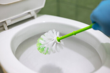 Housekeeper cleaning toilet with a brush. Keeping toilet clean and sanitized, regular cleaning of...