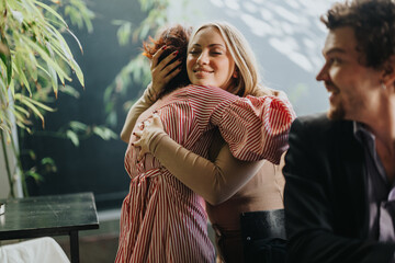 Two friends share a heartfelt hug at a cafe, exuding warmth and happiness. Their joyful interaction...