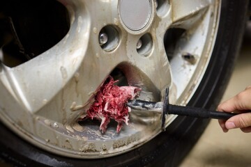 Cleaning car wheel thoroughly with brush and soap for maintenance and shiny result