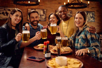 Portrait of multiracial group of happy friends gathering in pub and looking at camera.