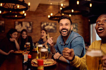 Cheerful man watching sports game with his friends in pub.