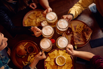 Above view of people toasting with beer in pub.