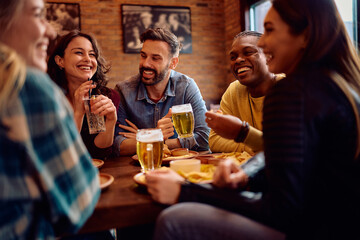 Carefree friends communicating while gathering in bar.