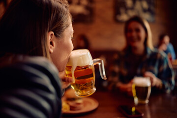 Close up of woman drinking beer in bar.
