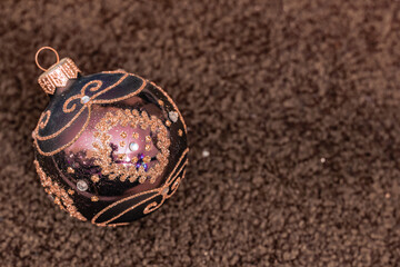 detailed burgundy Christmas ornament adorned with golden swirls and sparkling jewels, resting on a plush velvet background