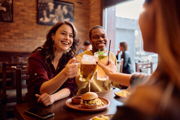 Happy woman having fun while toasting with her friends in bar.
